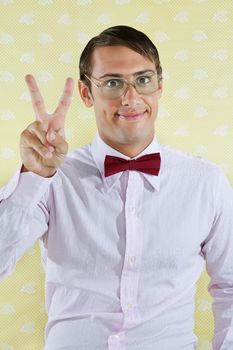 Portrait of male geek gesturing peace sign over yellow textured background