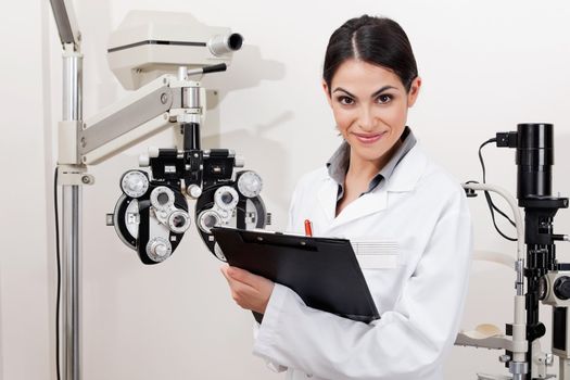 Portrait of a young optometrist smiling with clipboard at clinic