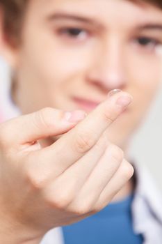 Optometrist holding contact lens in finger.