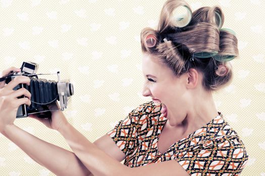 Woman holding a vintage 4x6 film camera on wallpaper.