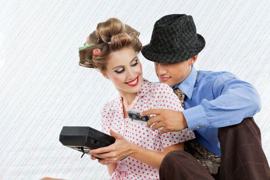 Retro styled young couple holding an old fashioned cassette player over textured background