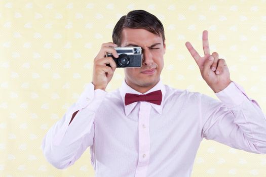 Man looking through old camera making peace sign.