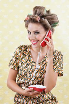 Portrait of an attractive young woman with hair curlers holding toy phone over a textured background