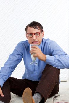 Man holding glass of milk sitting on rug.