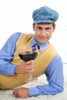 Man with large wine glass leaning on rug.