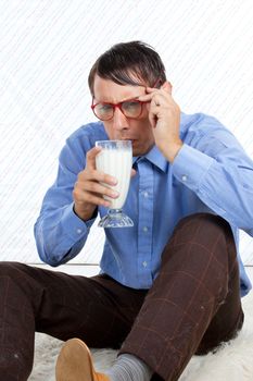 Man holding glass of milk sitting on rug.