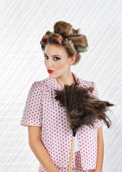 Portrait of young woman with hair curlers puckering while holding an ostrich feather duster