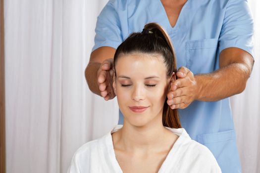 Relaxed young female with male masseuse standing behind