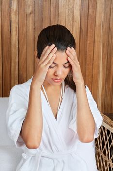 Beautiful mixed race woman in bathrobe holding her head in pain