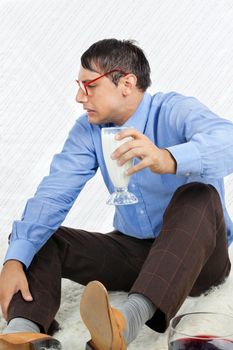 Young male geek making a face while holding glass healthy drink