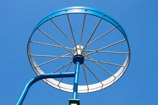 Metal painted detail in the form of a bicycle wheel on the blue sky background