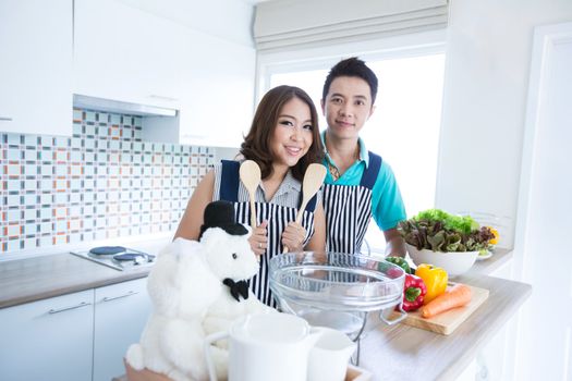 Young happy couples prepare vegetable salad in domestic kitchen