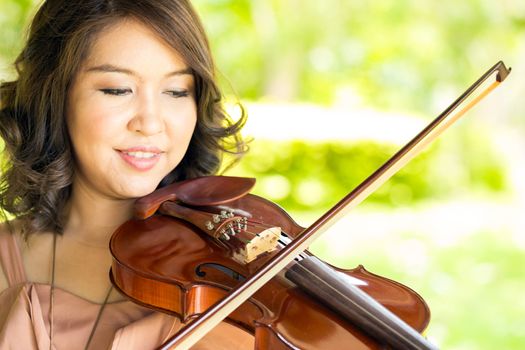 Young woman playing violin in garden