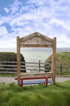 a red bench framed with a sea view and blue cloudy sky background with copy space