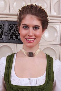 Portrait of a Bavarian girl in a dirndl with plaits and flowers in her hair