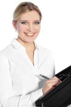 Happy young woman with a lovely smile looking at the camera as she stands writing in a handheld file, isolated on white