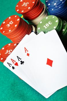 Set of four aces and poker chips on a green table