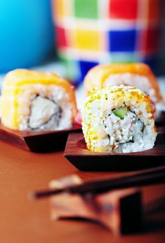 Close-up vertical photo of the rolled sushi with rice and cucumber on the table. Vibrant color and shallow depth of field for natural view