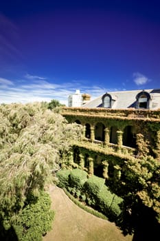 Photograph of an amazing castle covered with green trees and foliage under a blue sky.