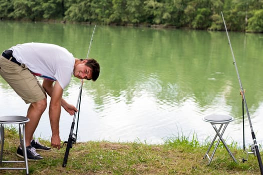 Brunette Man Fishing at a lake with green water