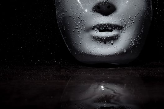 Wet plastic mask on a dark wooden background. Close-up photo