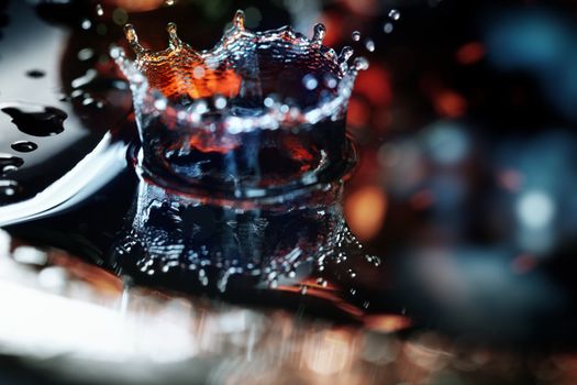 Extremely macro photo of the liquid drop falling on a wet colorful surface