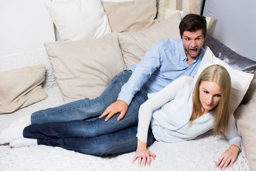 Young man screaming at woman while lying on couch