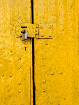 Padlock on an old yellow metallic door