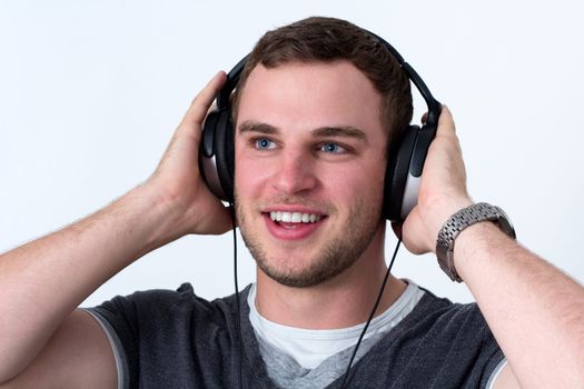 Close up of face of young man in grey t-shirt listening to music with earphones