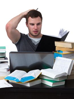 Young Student overwhelmed with studying with piles of books in front of him