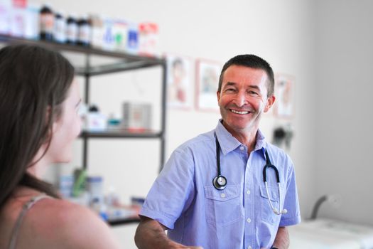 Smiling Male Doctor in his fifties Helping  brunette Woman