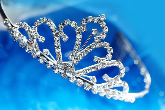 Close-up photo of the silver diadem with diamonds on a blue background with bokeh