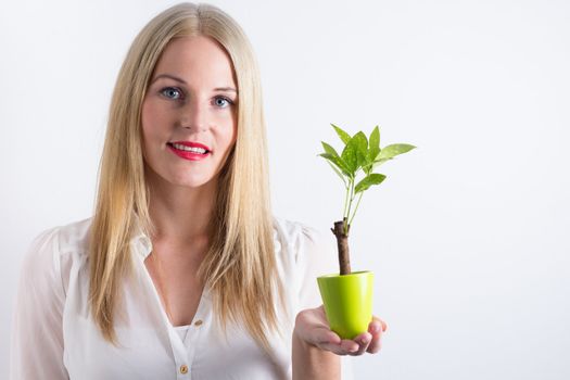 Blond woman holding a small green tree and smiling