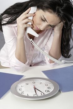 Woman on the phone watching a clock with a deadline approaching