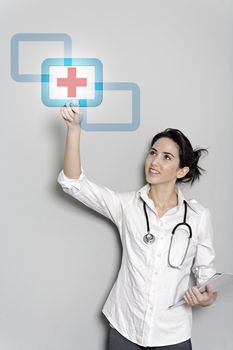 Beautiful female doctor pressing a concept red cross button