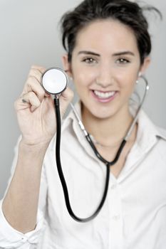 Attractive female doctor holding out and using a stethoscope