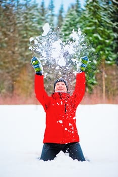 Female throwing a pile of snow up into the air. Female is in focus.