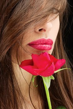 Pretty woman and wet red rose near her lips