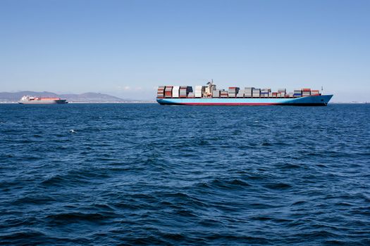 Picture of blue sea with a container ship driving along the horizon