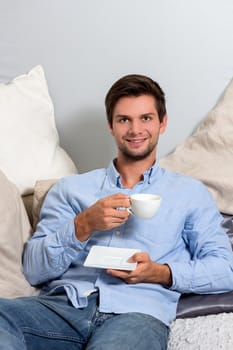 Young brunette man in blue clothing  enjoying a coffeebreak