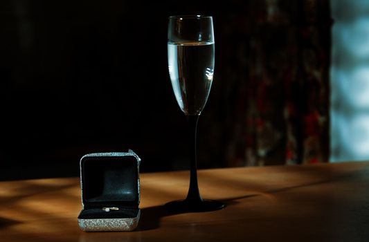Wedding ring with wine on a table in dark room