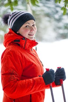 Portrait of a happy woman with ski poles in the winter woods