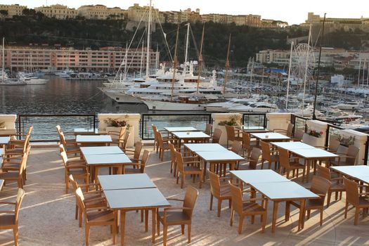 Restaurant at the harbor of monaco with yachts in the background