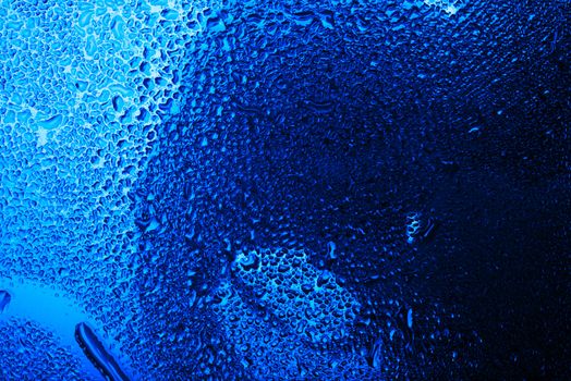 Wet glass with water drops in blue tone