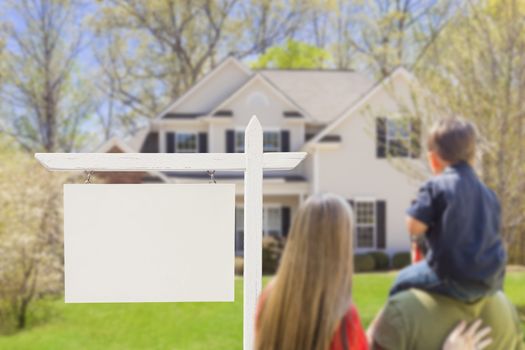 Mixed Race Young Family in Front of Blank Real Estate Sign and New House - Ready for Your Text.