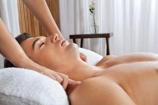 Young shirtless man receiving massage from masseur at health spa
