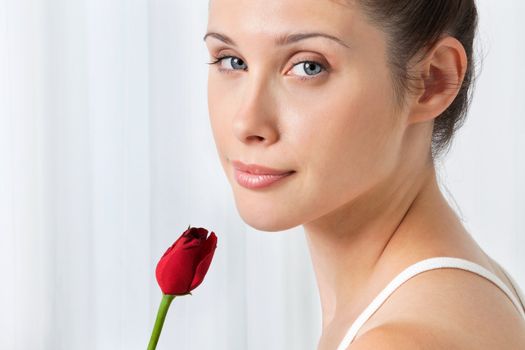 Portrait of pretty young female with red rose over white background