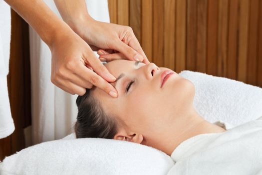 Pretty young female receiving a head massage at health spa