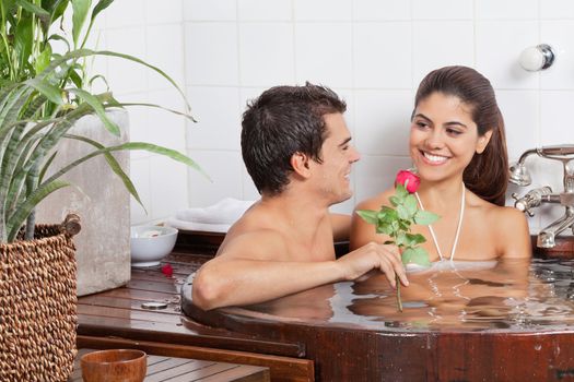 Happy multiethnic young couple relaxing in bathtub at spa