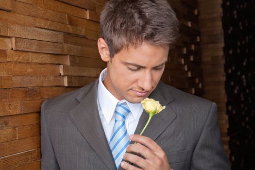 Young male corporate executive in a formal business suit holding yellow rose